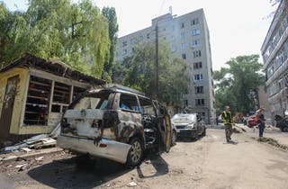 Workers clean a street next to damaged cars following what local authorities said was a Ukrainian drone attack, amid the Russia-Ukraine conflict, in the town of Voronezh